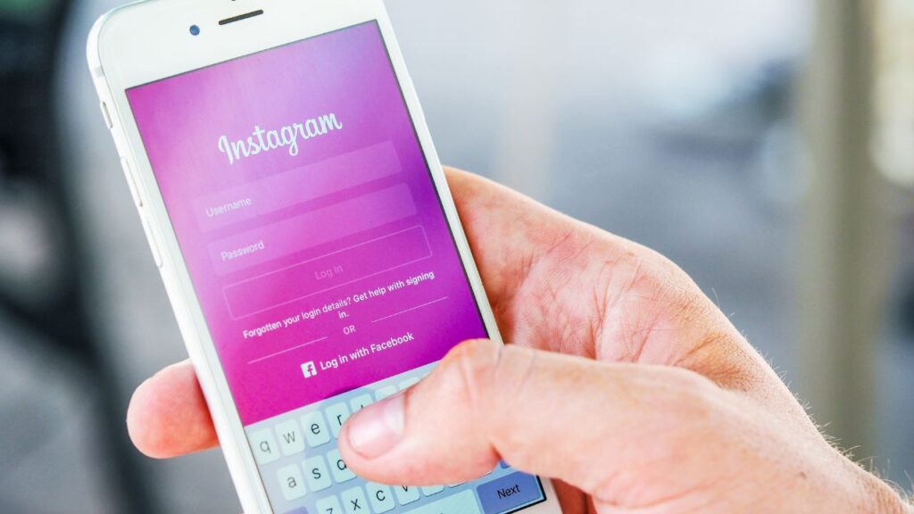 Tela de login do Instagram exibida em um smartphone, segurado por uma mão masculina. Destaque para o campo de entrada de dados. Palavra-chave: o que é a bio do Instagram.