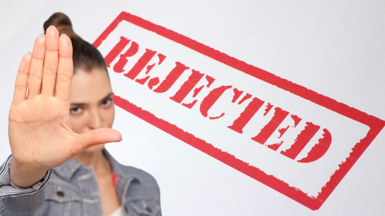 Mão com marcador vermelho riscando uma figura triste entre várias figuras sorridentes desenhadas — o que é taxa de rejeição.