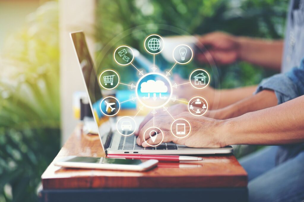 Mãos digitando em notebook com ícones de canais conectados ao redor, simbolizando atendimento omnichannel.