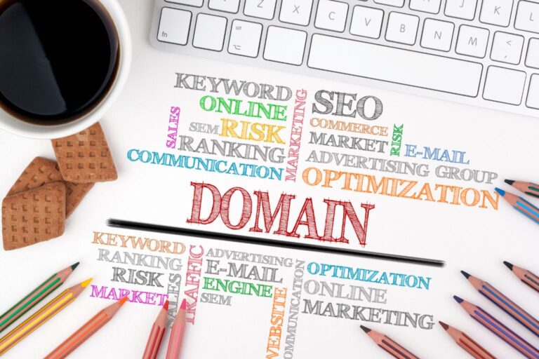 Papel com palavras-chave coloridas em volta da palavra "domain", rodeado de itens de escritório.