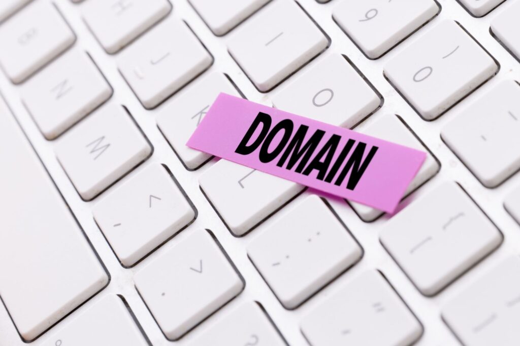 Teclado branco com etiqueta rosa escrita "domain", destacando o foco em autoridade de domínio no SEO.