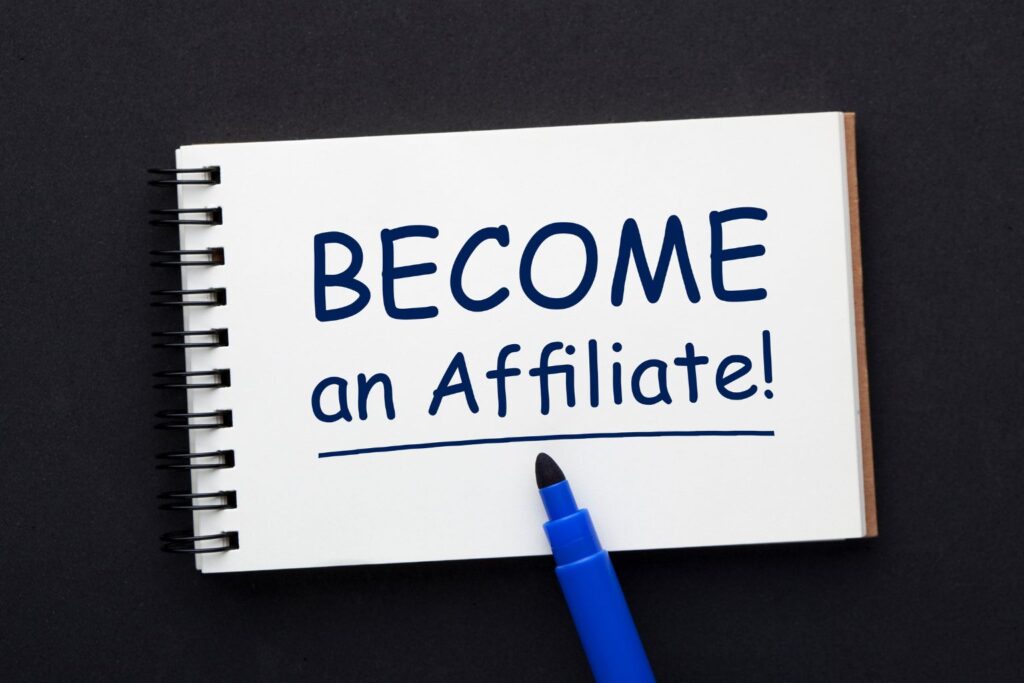 Caderno com a frase “Become an Affiliate” escrita à mão. Palavra-chave: afiliado digital.