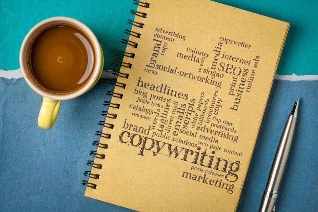 Caderno com palavras relacionadas a copywriting e marketing, ao lado de café – copywriting para empresas.