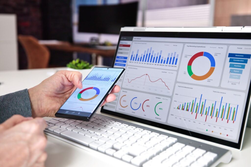Pessoa utilizando smartphone e laptop com gráficos coloridos e métricas de web analytics